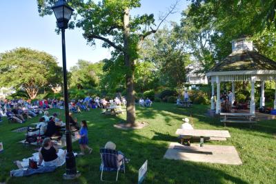 st michaels concert in muskrat park people sitting in the park listening to music by the band who is performing under the gazebo